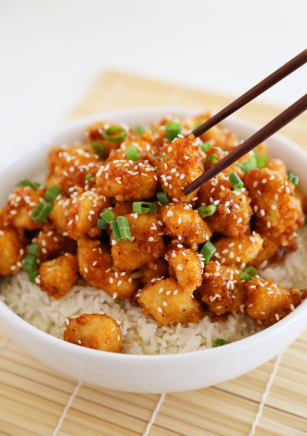 Crispy Baked Honey Garlic Chicken – Chicken bites in a sticky honey-Sriracha sauce are a weeknight meal or party appetizer! Thecomfortofcooking.com