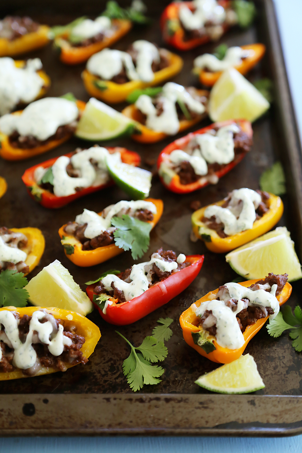 Mini Taco Stuffed Peppers with Cilantro Cream Sauce - Easy 5-ingredient spicy taco stuffed peppers with a creamy cool sauce. Thecomfortofcooking.com