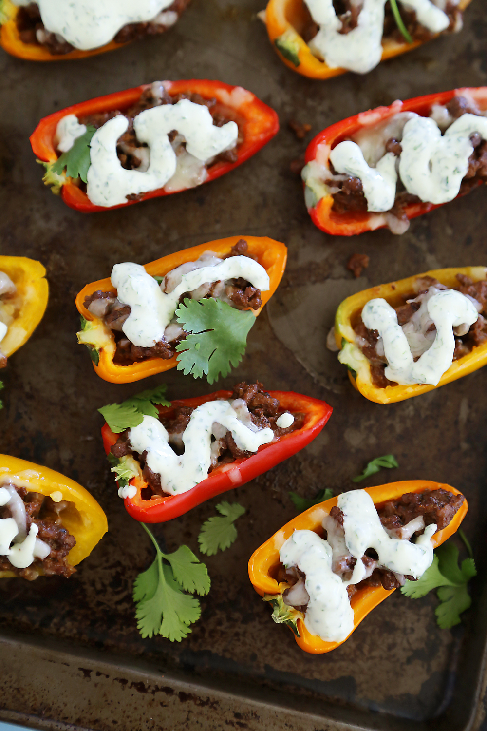 Mini Taco Stuffed Peppers with Cilantro Cream Sauce - Easy 5-ingredient spicy taco stuffed peppers with a creamy cool sauce. Thecomfortofcooking.com