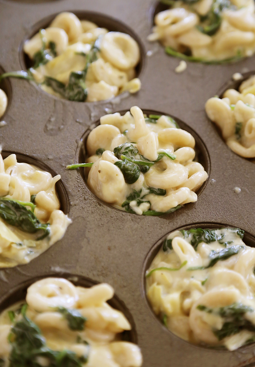 Spinach and Artichoke Macaroni and Cheese Bites – Enjoy the flavor of your favorite delicious dip in a creamy, cheesy mini mac and cheese. So good! thecomfortofcooking.com