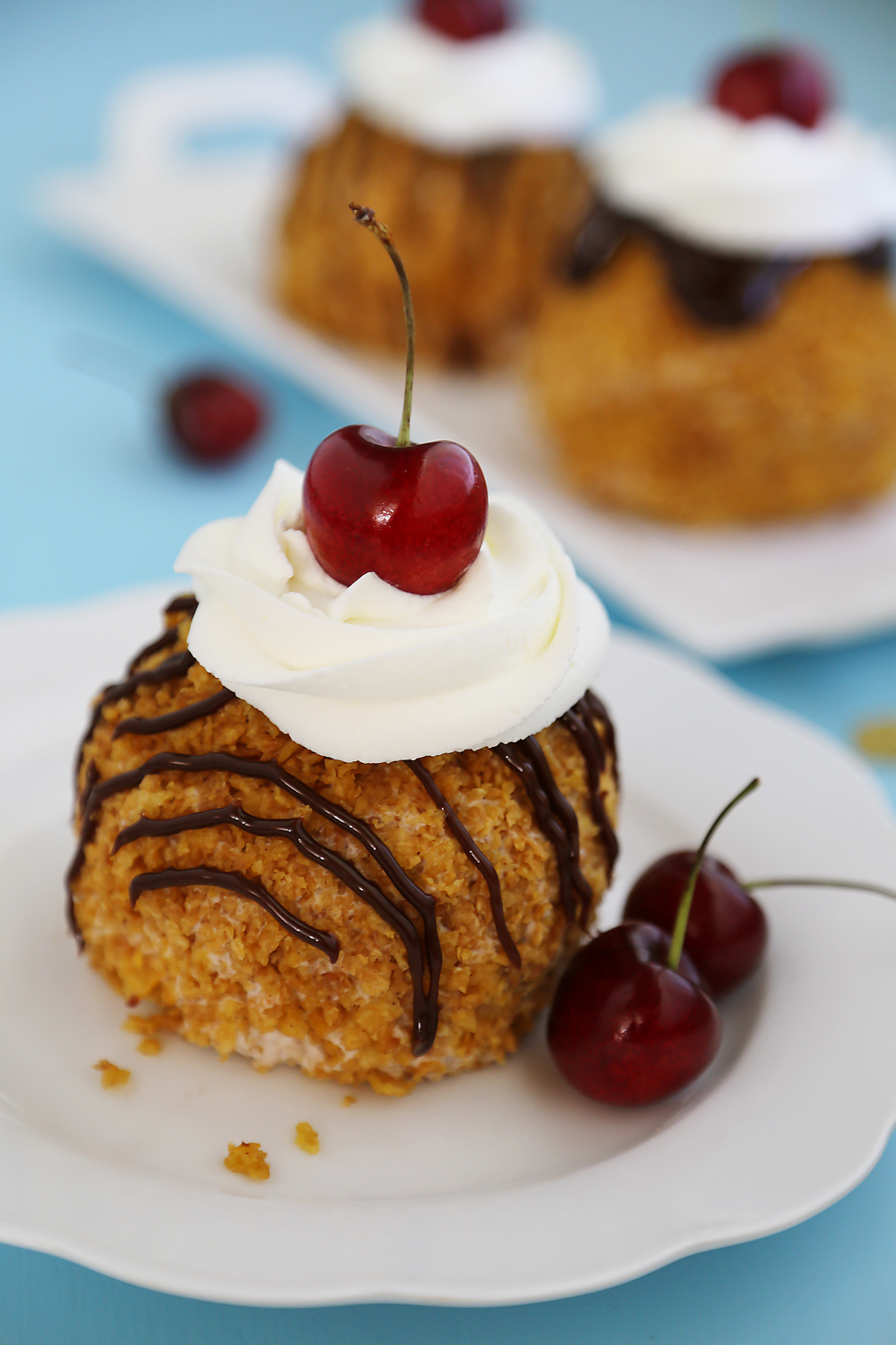 Easy Mexican Fried Ice Cream - Creamy ice cream rolled in crispy cornflakes, topped with chocolate, cream and cherries. So easy + elegant! Thecomfortofcooking.com