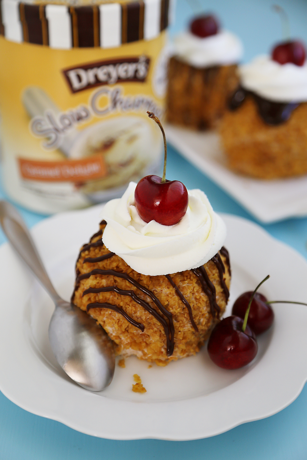 Easy Mexican Fried Ice Cream - Creamy ice cream rolled in crispy cornflakes, topped with chocolate, cream and cherries. So easy + elegant! Thecomfortofcooking.com