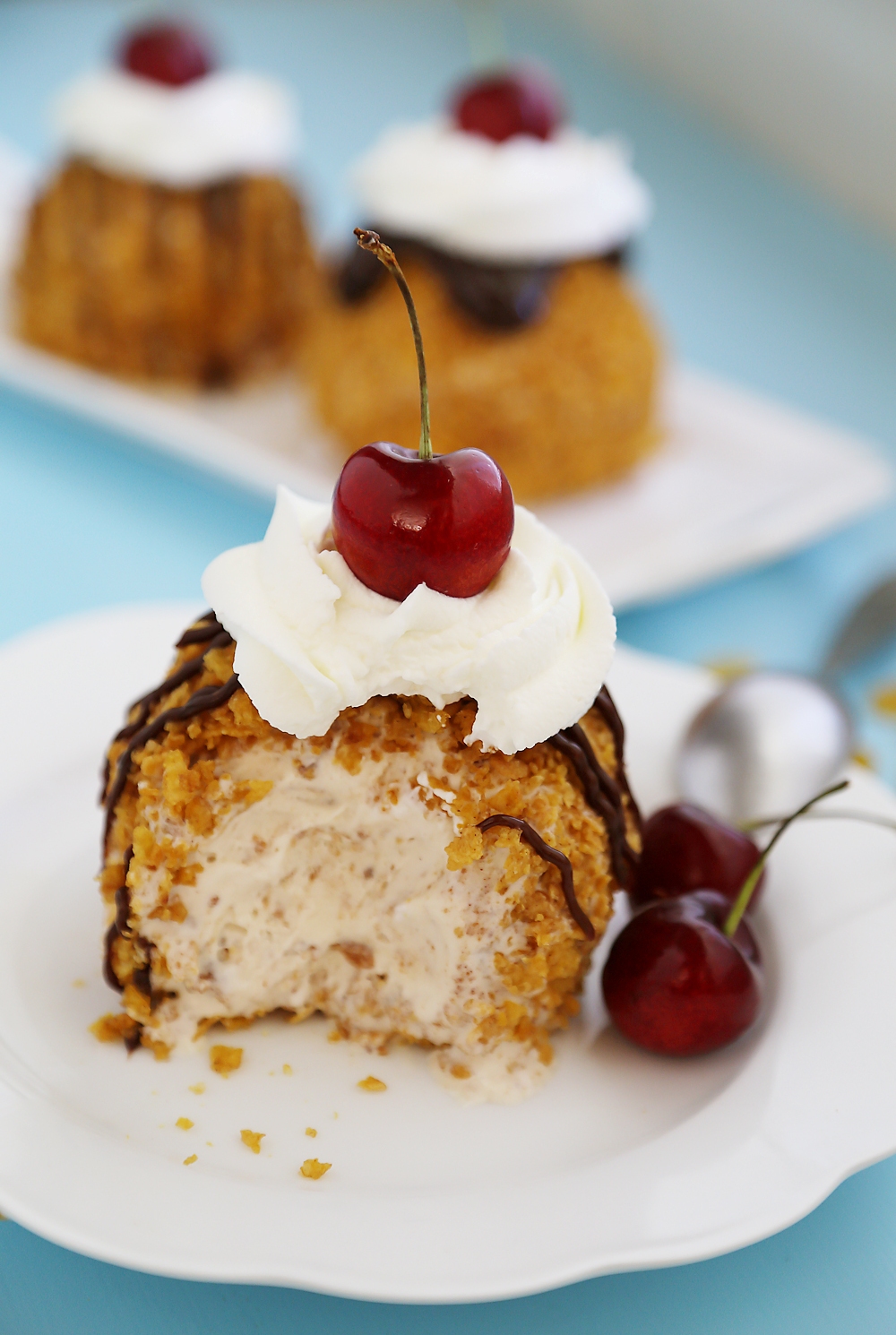 Easy Mexican Fried Ice Cream - Creamy ice cream rolled in crispy cornflakes, topped with chocolate, cream and cherries. So easy + elegant! Thecomfortofcooking.com