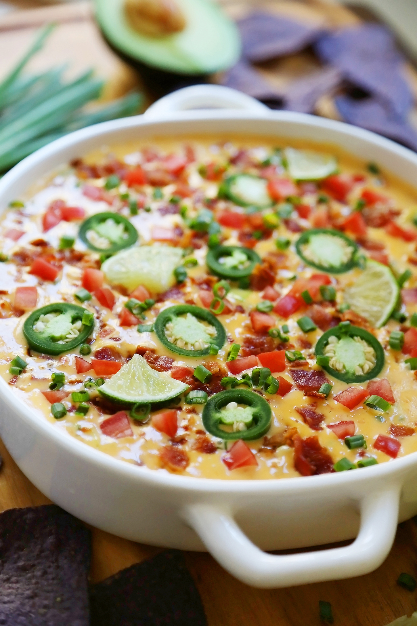 2-Ingredient CrockPot Queso Dip - So easy, cheesy and full of flavor for parties and lazy weekends in. Load it up with bacon, tomatoes, jalapenos and your favorite fixin's! Thecomfortofcooking.com