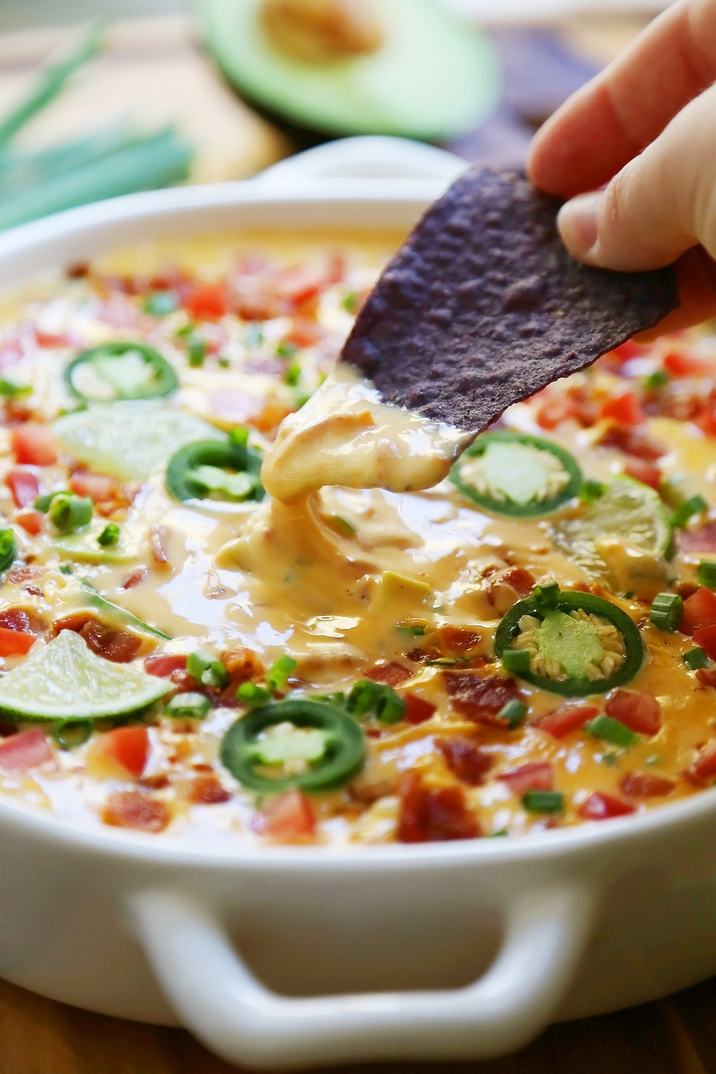 2-Ingredient CrockPot Queso Dip - So easy, cheesy and full of flavor for parties and lazy weekends in. Load it up with bacon, tomatoes, jalapenos and your favorite fixin's! Thecomfortofcooking.com