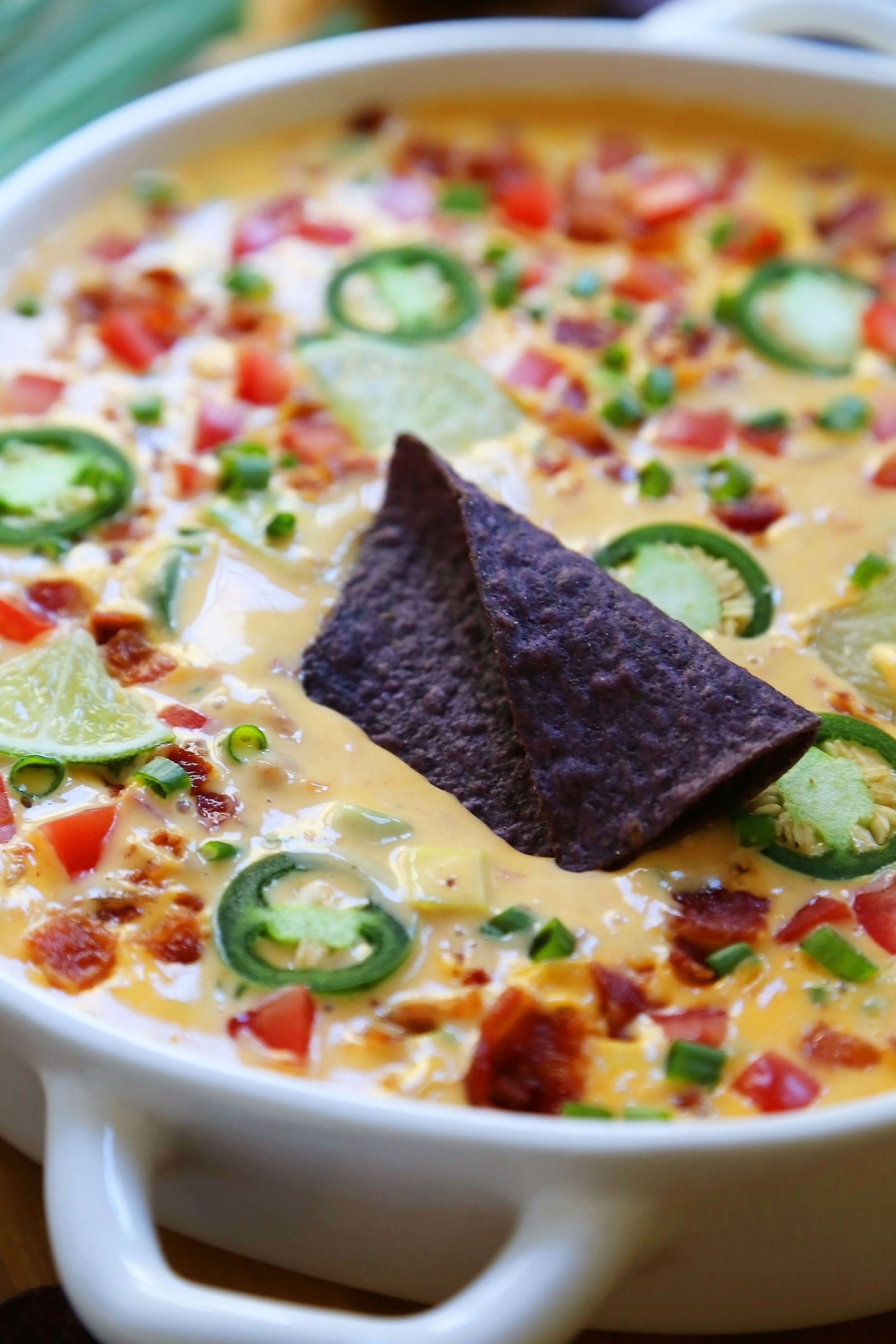 2-Ingredient CrockPot Queso Dip - So easy, cheesy and full of flavor for parties and lazy weekends in. Load it up with bacon, tomatoes, jalapenos and your favorite fixin's! Thecomfortofcooking.com