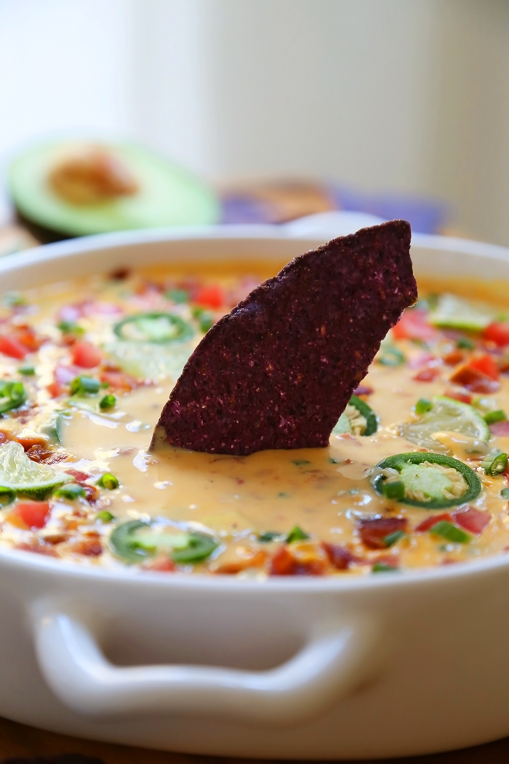 2-Ingredient CrockPot Queso Dip - So easy, cheesy and full of flavor for parties and lazy weekends in. Load it up with bacon, tomatoes, jalapenos and your favorite fixin's! Thecomfortofcooking.com